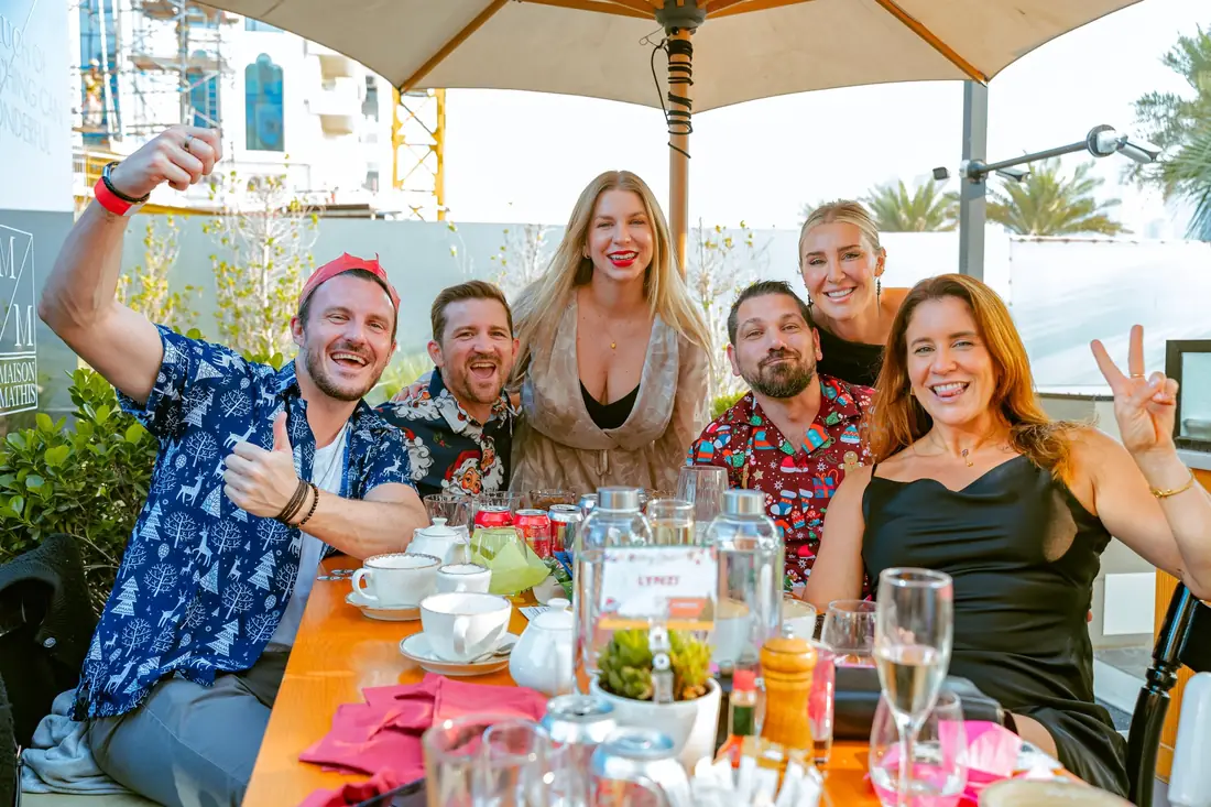 A group of friends laughing together at a sunny terrace table