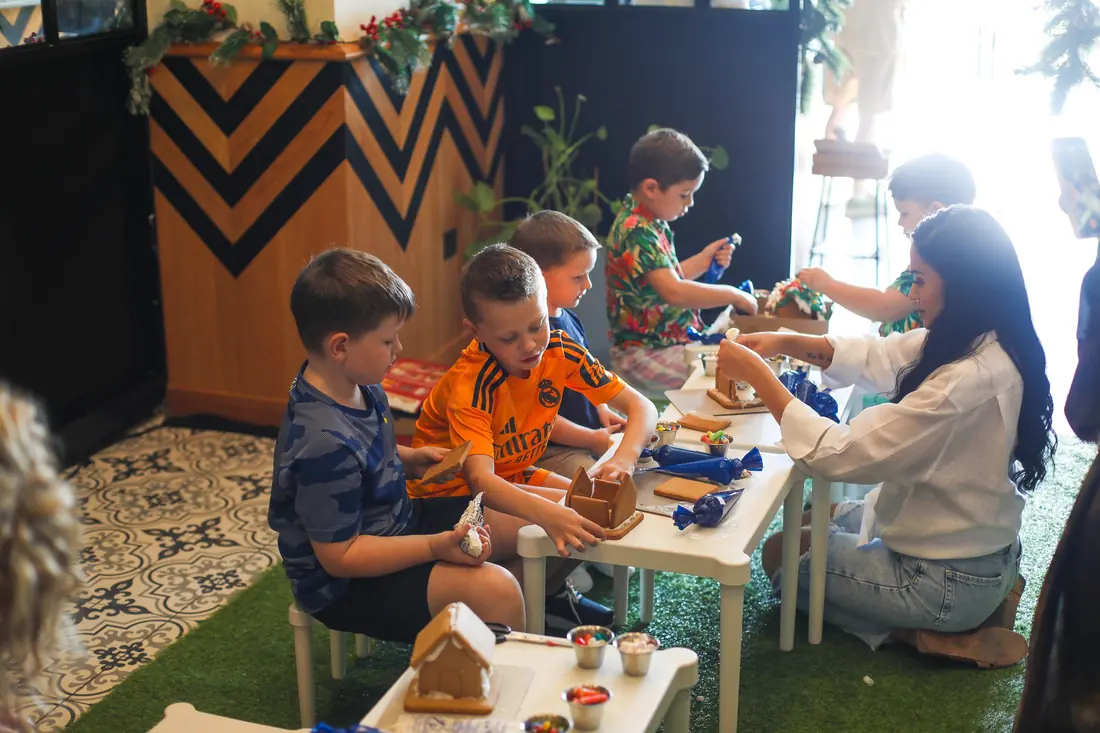 Children decorating gingerbread houses at a table at Maison Mathis voco The Palm