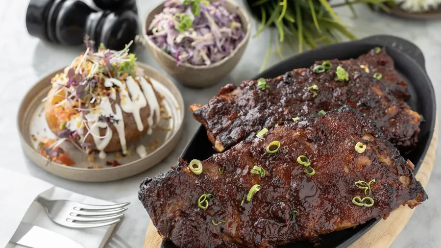 Glazed barbecue pork ribs with a loaded baked potato and slaw