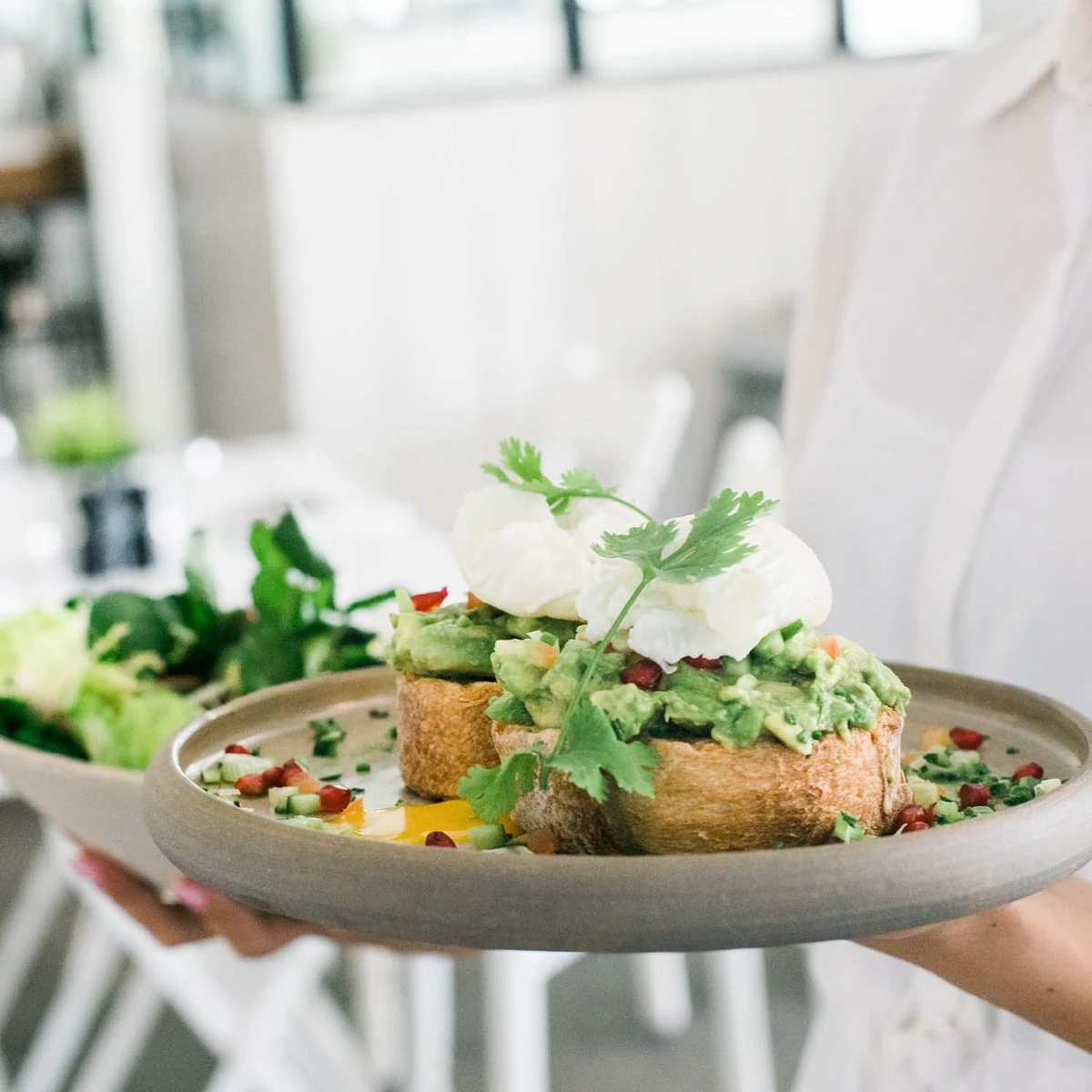 Poached eggs on smashed avocado and sourdough toast, served on a stoneware plate