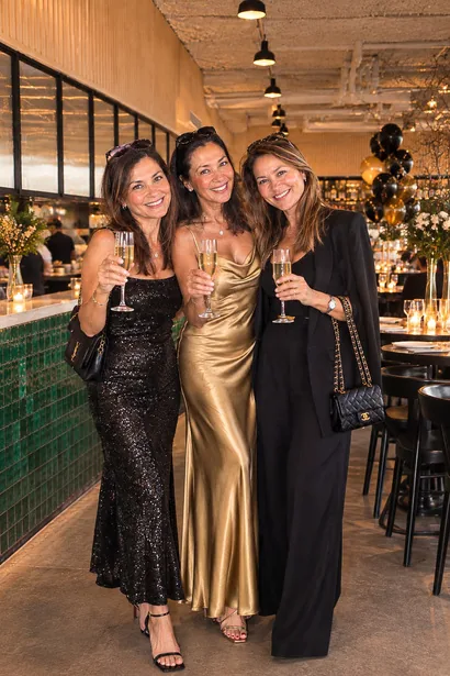 Three guests in evening wear raising glasses at the bar
